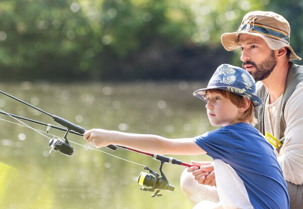 Father and son fishing in lake while sitting on pier