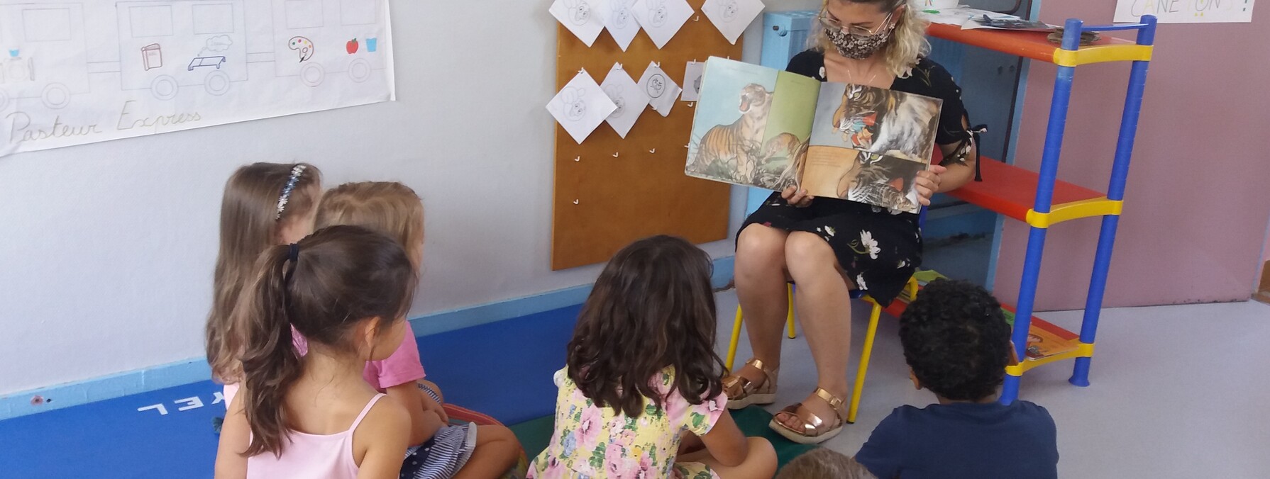 Des enfants sont réunis autour d'une animatrice qui leur lit une histoire