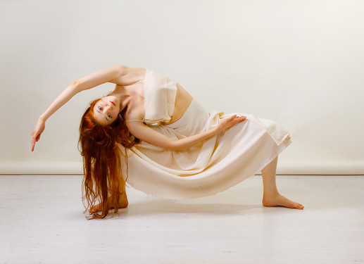 Young redhead woman does stretching and yoga poses, dancing contemporary dance, posing in studio, . Copy space