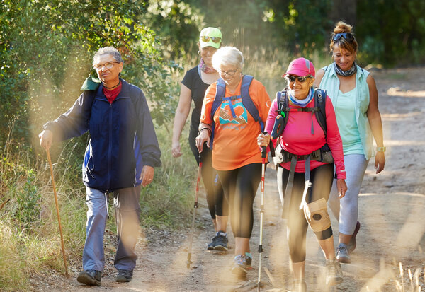 Nature, walking and senior group hiking in forest for exercise, health and wellness with cardio outdoor workout. Fitness, healthy and elderly friends or retirement club trekking on path in the woods