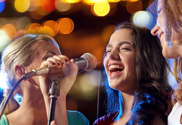 happy young women singing karaoke in night club