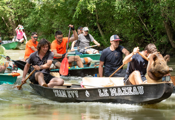 Des équipes pagaient énergiquement en barques lors de la course, dont l'équipe « Team EVV Le Mazeau » au premier plan