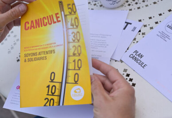 Brochure Plan Canicule « Soyons attentifs & solidaires » illustrée d'un thermomètre, tenue entre les mains