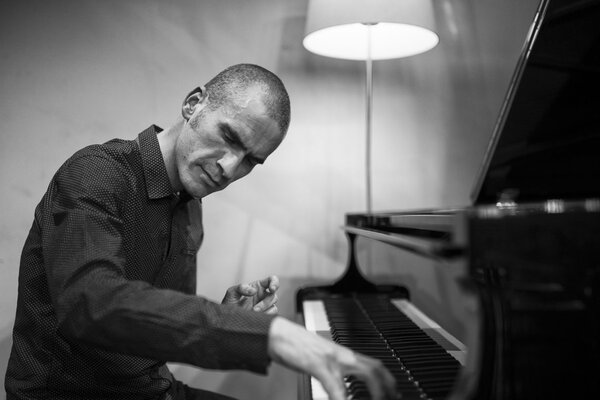 Un pianiste concentré interprète un morceau sur un piano à queue dans une salle à l'éclairage tamisé