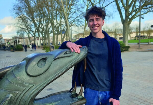 Lukas Jarnouen souriant, la main posée sur un dragon de la rue Ricard