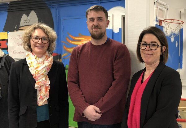 Trois personnes dans la salle de loisirs du quartier Tour Chabot, devant des fresques murales colorées