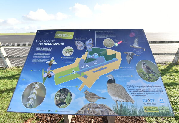 Panneau 'Réservoir de biodiversité' installé sur site, avec plan cartographié de l'aérodrome et espèces animales et végétales recensées