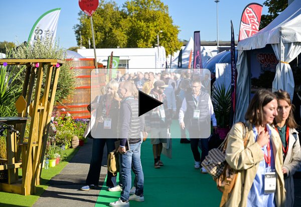 Professionnels munis de badges déambulant dans les allées extérieures du salon entre les stands des exposants