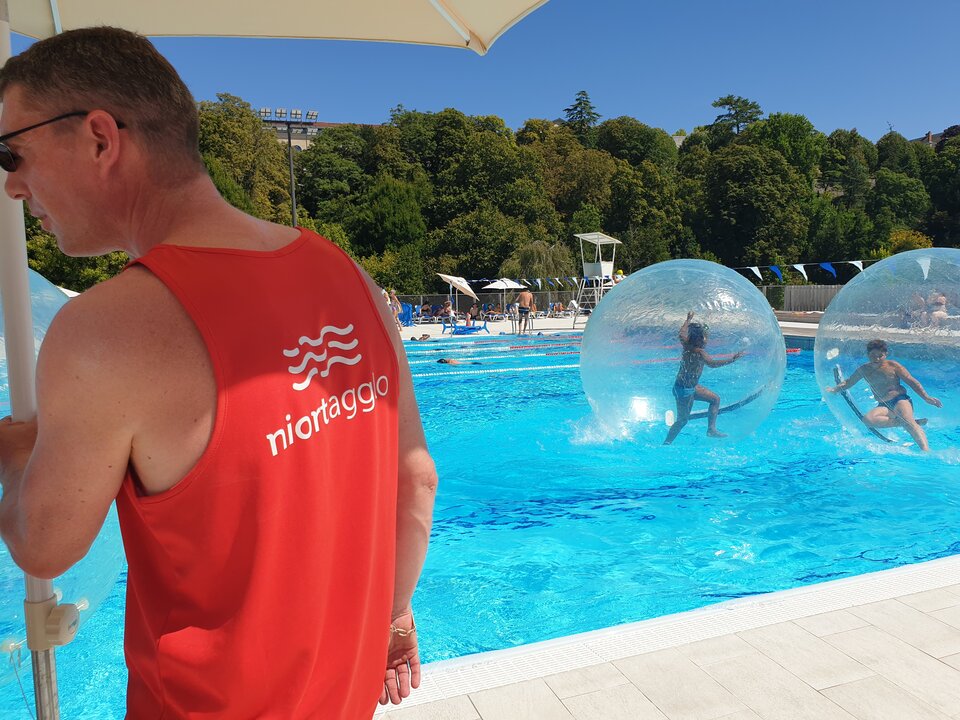 Un agent Niort Agglo surveille depuis le bord deux participants s'amusant dans des sphères transparentes sur l'eau.