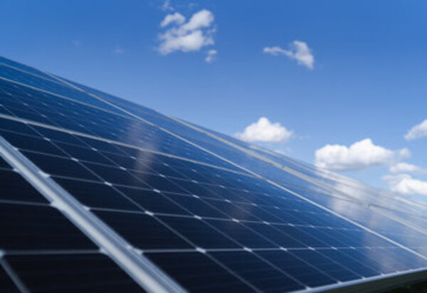 Gros plan sur des modules solaires à cellules bleu foncé disposés en rangées sous un ciel ensoleillé