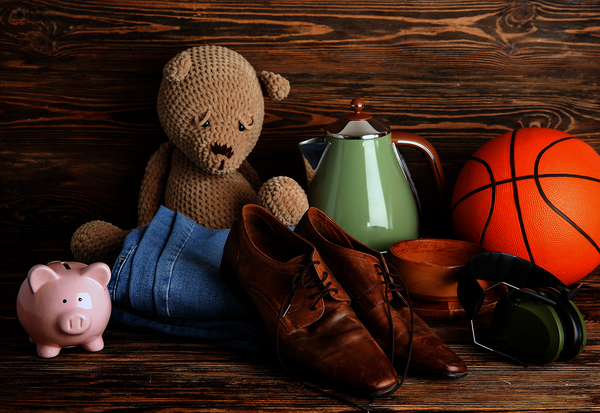 Peluche tricotée, jean, chaussures en cuir, théière verte, ballon de basket et casque audio posés sur un plancher en bois