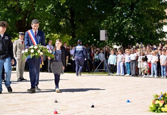Jérôme Baloge en écharpe tricolore et des enfants portent une gerbe lors  de la cérémonie