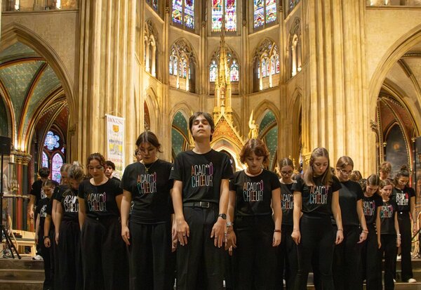 Les choristes d'ACAD'ÔCHŒUR en formation dans une nef gothique ornée de vitraux colorés