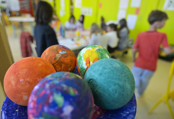 Globes peints par des enfants représentant des planètes colorées, lors d'une activité créative périscolaire