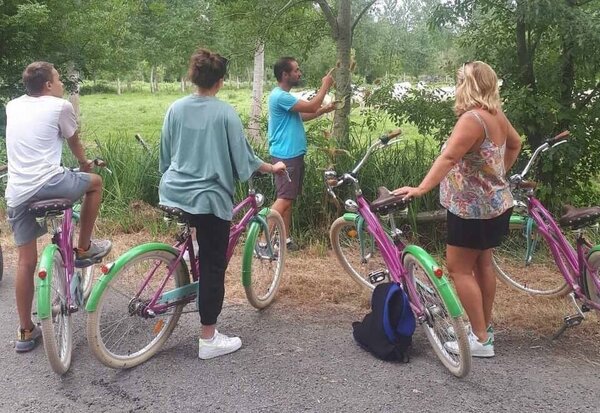 Un guide désigne des éléments de la végétation à trois participants à vélo, arrêtés le long d'un canal